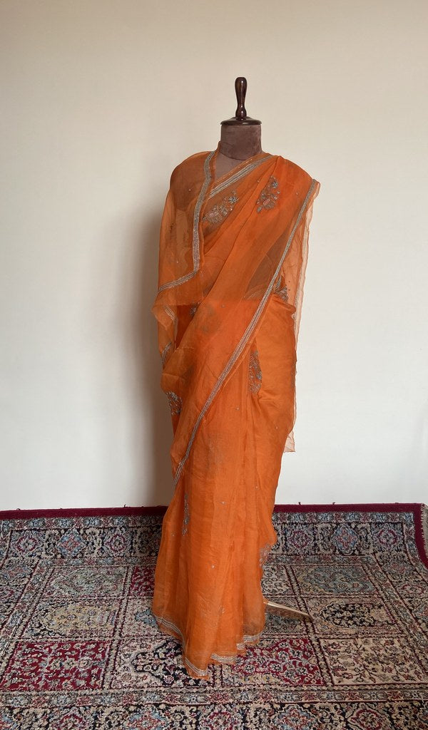 Tangerine orange organza silk saree draped on the mannequin, front view